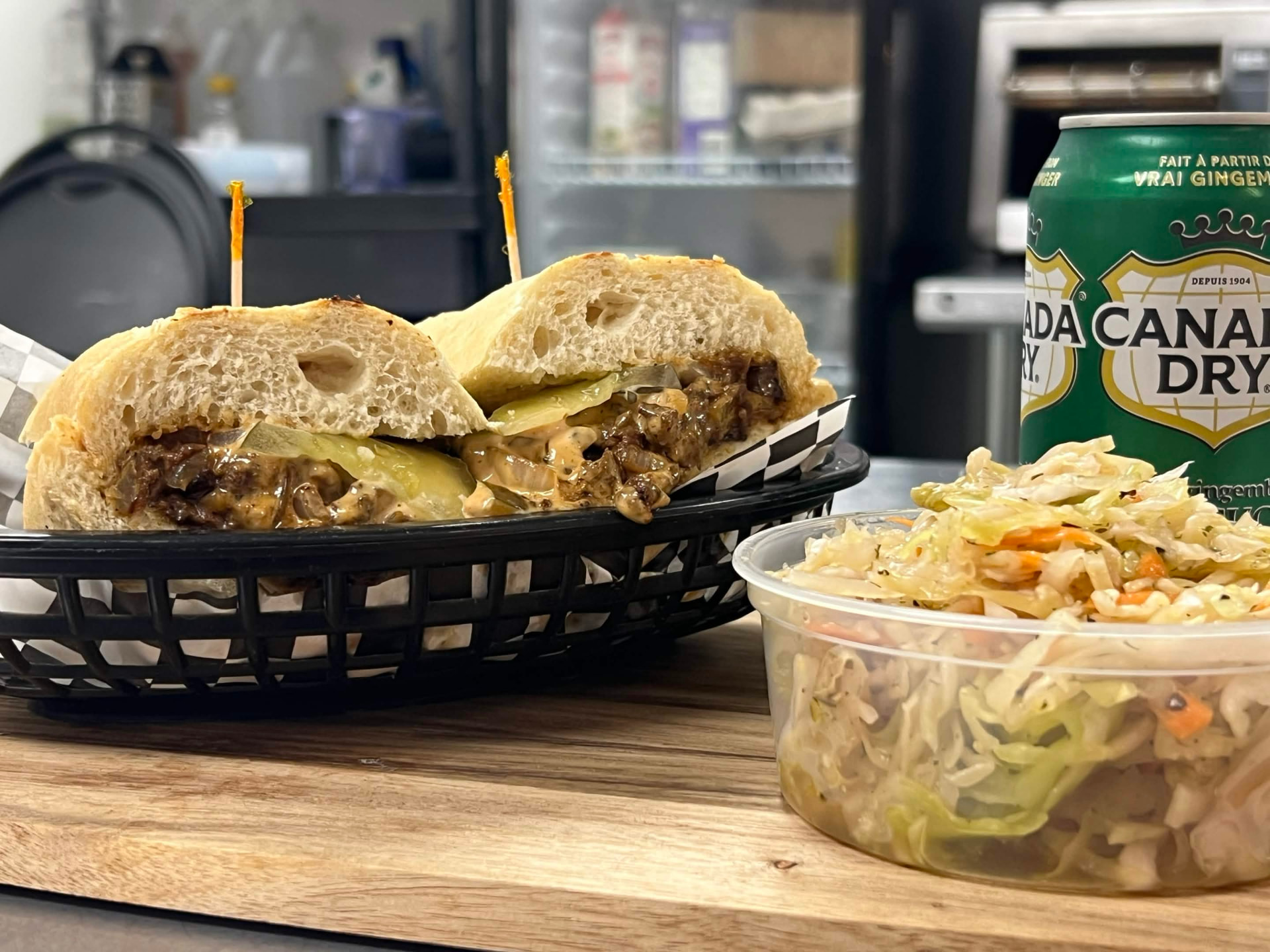 Big Deez Philly cheesesteak in a basket with a side of house slaw and a can of Canada Dry