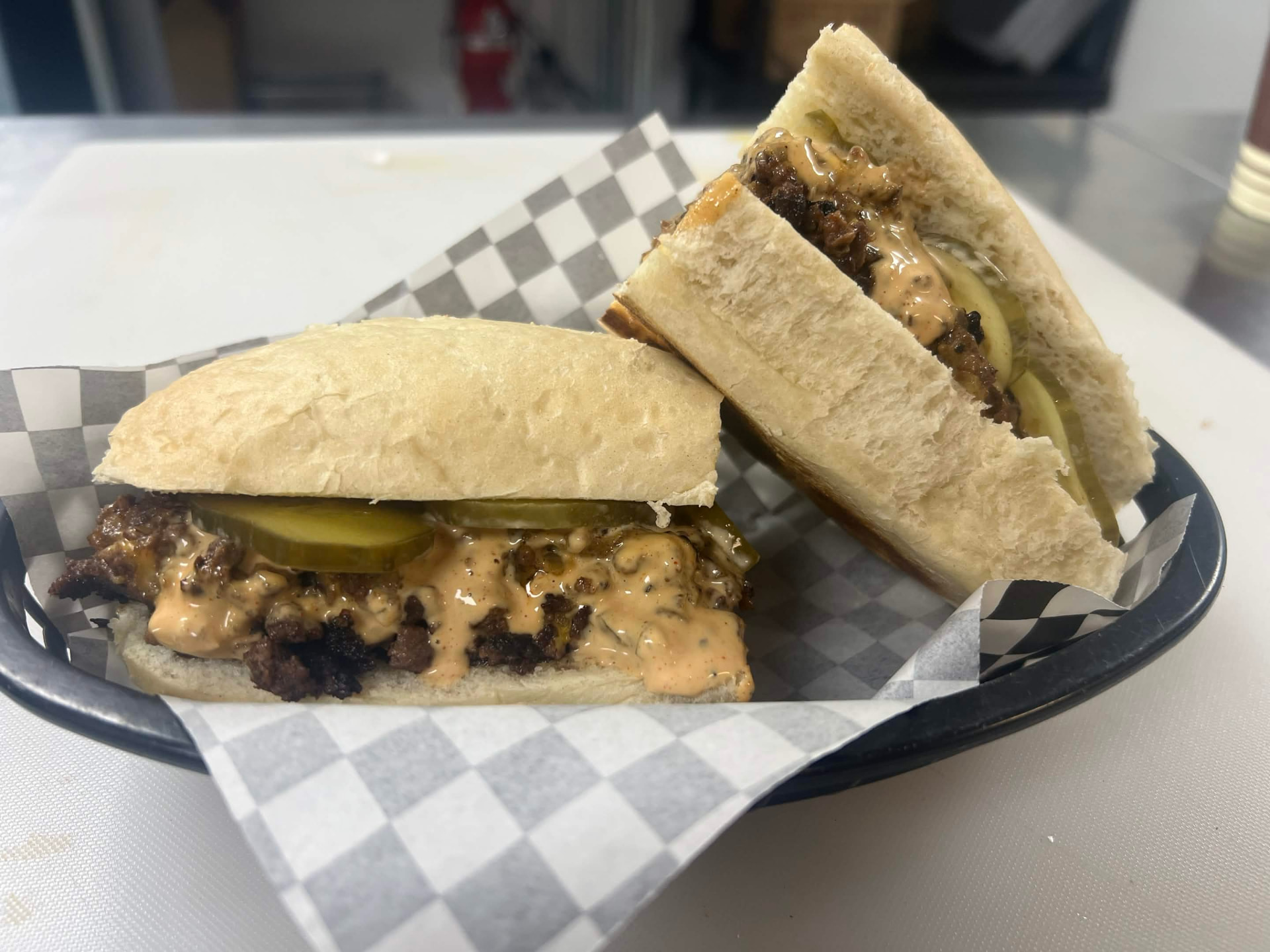 Chopped cheese smash burger sandwich cut in half with pickles and house burger sauce