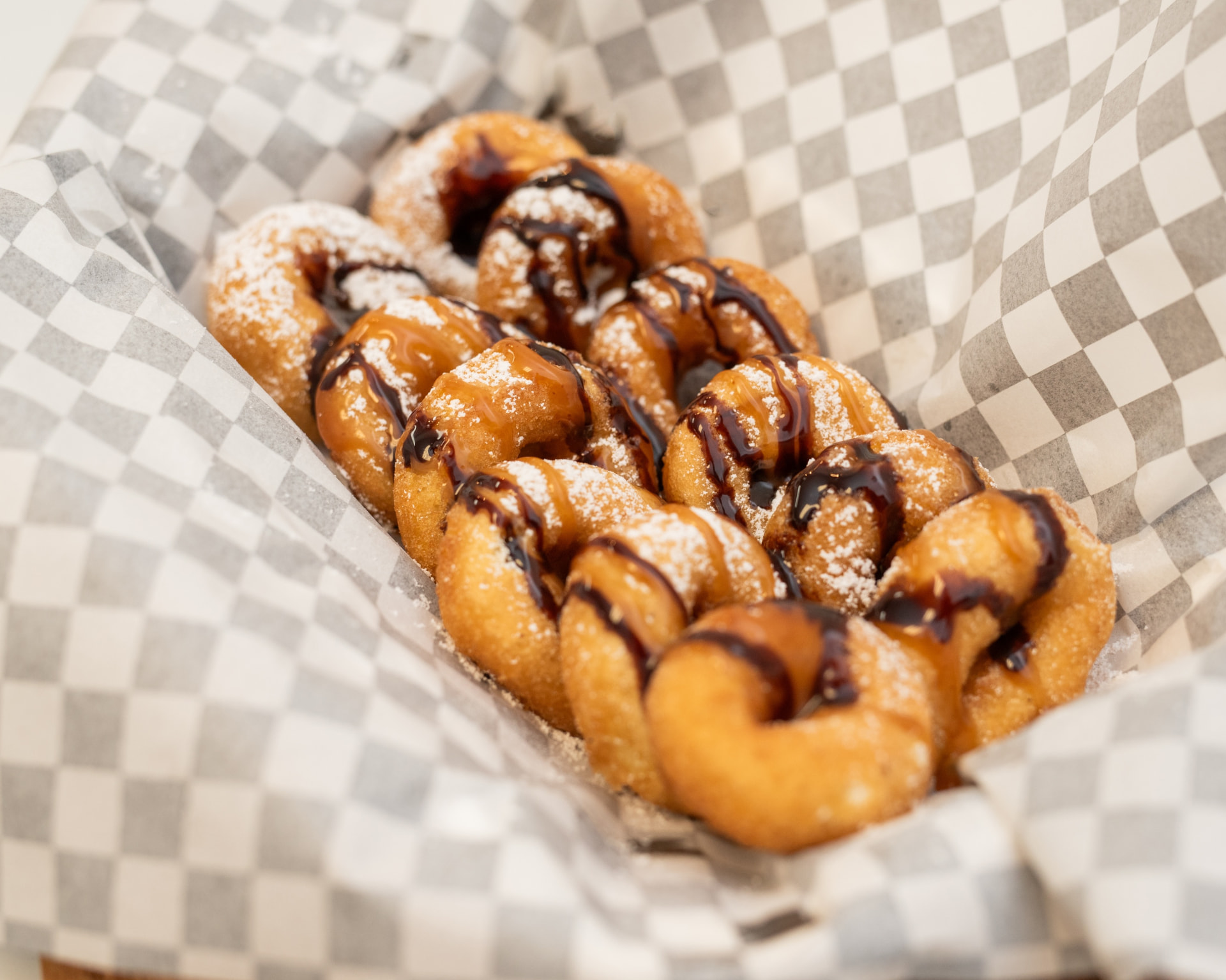 Mini donuts drizzled with chocolate and peanut butter sauce on checkered paper